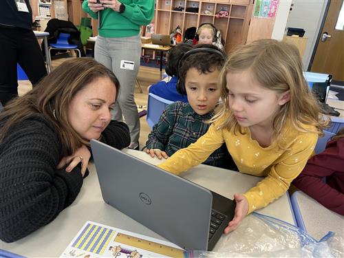 Students and woman gathered around computer